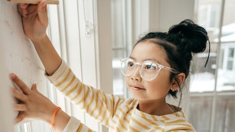 young girl with glasses writing on calendar planning for college