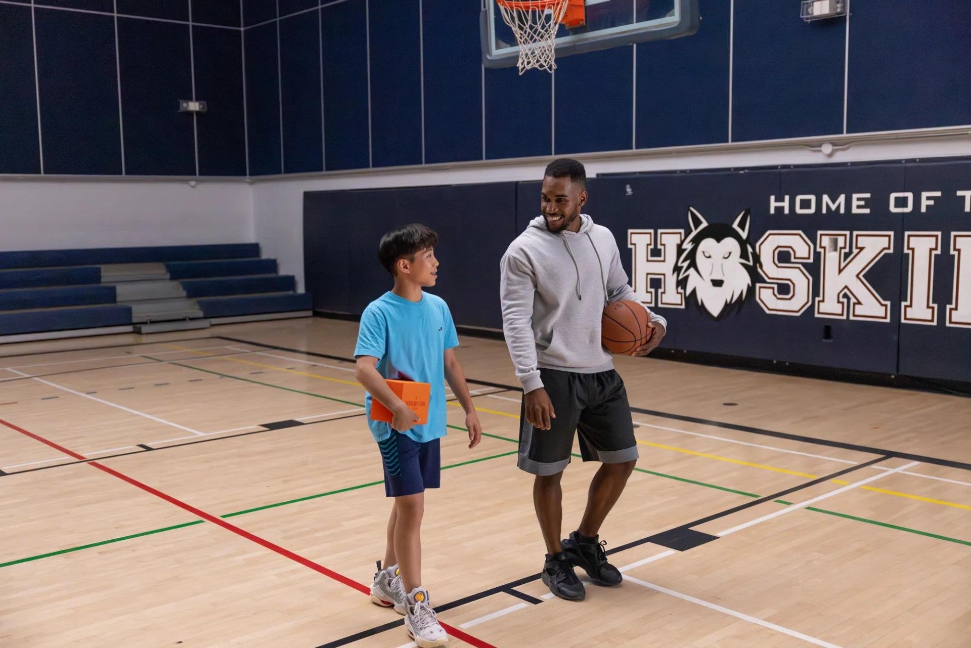 Student and coach walking on a basketball court.